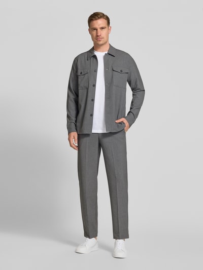 Männermodel trägt Slim Fit Stoffhose mit Viskose-Anteil von Lindbergh in Grau, Elastischer-Material-Mix, Bügelfalte, Eingrifftaschen, Ganzkörperansicht von vorne.