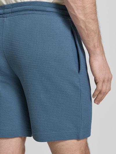 Männermodel trägt Regular Fit Sweatshorts aus Baumwoll-Mix Modell 'AUSTIN' von HUGO in Blau, Piqué-Struktur, Nahaufnahme Rückansicht.