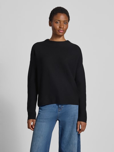 Frauenmodel trägt Loose Fit Pullover aus reiner Baumwolle Modell 'MERINAA' von ARMEDANGELS in Schwarz, glatte Textur, Ganzkörperansicht von vorne.