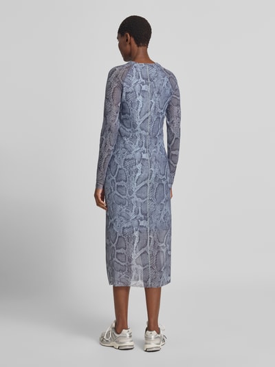Frauenmodel trägt Midikleid mit Schlangenmuster von Marc Cain in Blau-Grau, eng anliegend, semitransparent, Rückansicht Ganzkörperansicht.