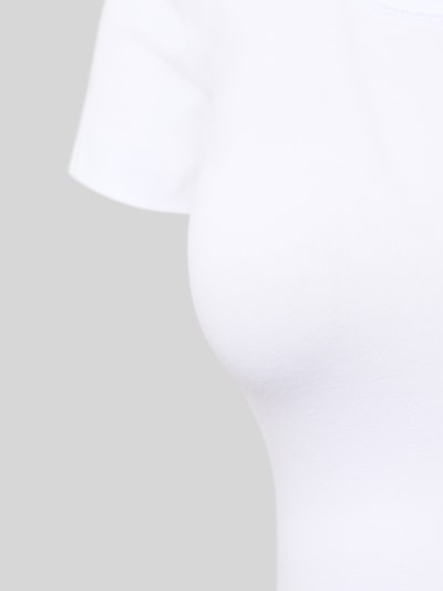 Frauenmodel trägt T-Shirt mit Logo-Print von HUGO in Weiß, Baumwoll-Elasthan-Mix, leicht taillierter Schnitt, Nahaufnahme Oberkörper.