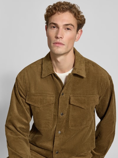 Männermodel trägt Regular Fit Hemdjacke aus Cord Modell 'David' von Wood Wood in Braun, strukturierte Oberfläche, Nahaufnahme Oberkörper. Herren Hemdjacke von Wood Wood, reine Baumwolle, Regular Fit, Kentkragen, Brusttaschen, Rückenlänge bei Größe M 73 cm.