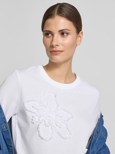 Frauenmodel trägt Regular Fit T-Shirt mit Rüschenbesatz von Comma, Reine Baumwolle, Rundhalsausschnitt, Weiß, Nahaufnahme Oberkörper.