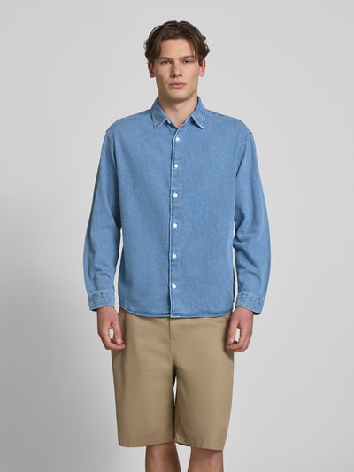 Männermodel trägt Regular Fit Jeanshemd mit Kentkragen Modell 'NORREBRO' von Jack & Jones aus reiner Baumwolle, Ganzkörperansicht von vorne.