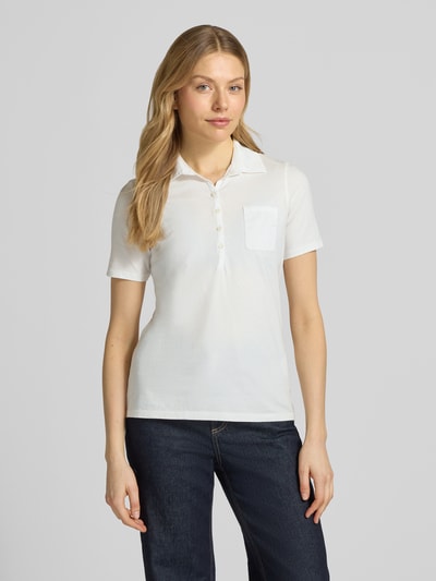 Kobiece modelka nosi Regular Fit Poloshirt aus reiner Baumwolle von Marc O'Polo, efekt: jednolity kolor, krój regular fit, aplikacja: nadruk z logo, kształt kołnierza: kołnierzyk polo, zapięcie: krótka listwa guzikowa, rękaw: krótki rękaw, brustasza, wykończenie materiału: dżersej, materiał: bawełna, kolor biały, gładka struktura; Ganzkörperansicht von vorne.