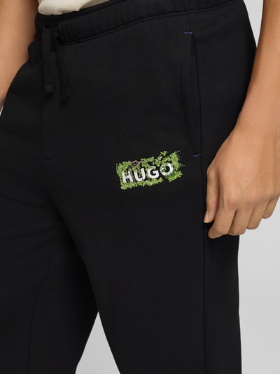 Männermodel trägt zwarte regular fit sweathose uit pure katoen model 'Nivion' van HUGO, Heren Sweathose, detailopname rechterdij.