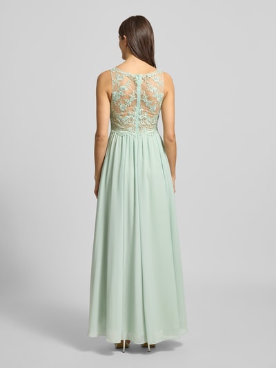 Frauenmodel trägt Regular Fit Abendkleid mit floralem Spitzenbesatz von Laona, semitransparentes Design in Mintgrün, blickdichter Unterrock, Ganzkörperansicht Rückansicht.