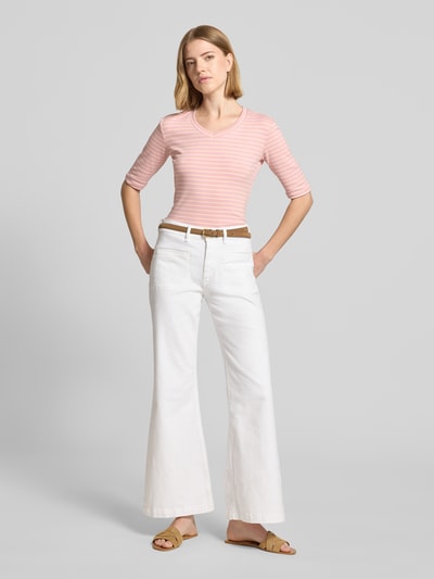 Frauenmodel trägt Longsleeve mit 3/4-Arm und V-Ausschnitt von Christian Berg Woman aus Baumwoll-Mix mit Stretch-Anteil, Streifenmuster in Rosatönen, Straight Fit, Rückenlänge bei Größe S 54 cm, kombiniert mit weißer Hose; Ganzkörperansicht von vorne.