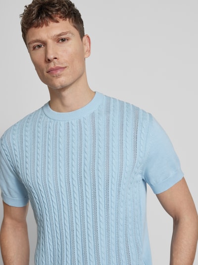 Männermodel trägt T-Shirt mit Zopfmuster von Lindbergh in Hellblau, reine Baumwolle mit Strick-Optik, Nahaufnahme Oberkörper.