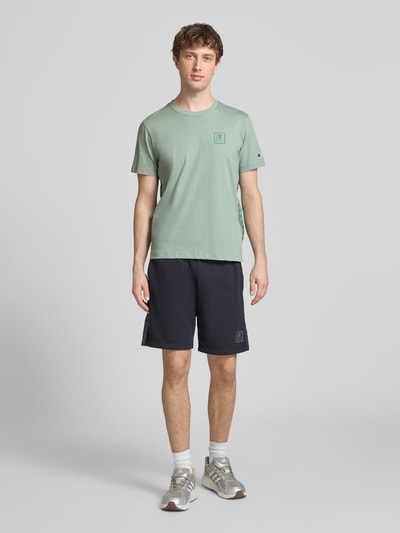 Männermodel trägt T-Shirt mit Logo und Rundhalsausschnitt von CHAMPION in Mintgrün, reine Baumwolle, Regular Fit, Ganzkörperansicht von vorne