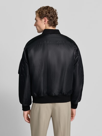 Männermodel trägt Bomberjacke mit Stretch-Anteil von Emporio Armani in Schwarz mit Satin-Textur, lockere Passform, Rückenansicht.