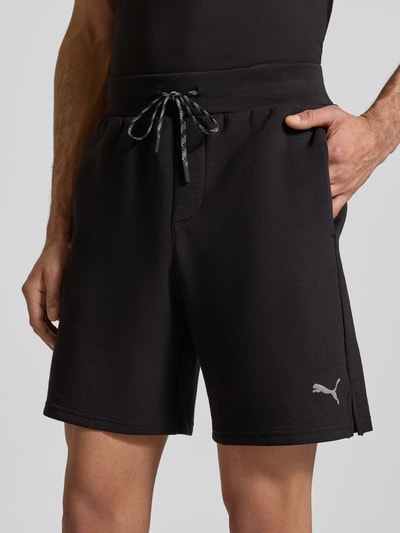 Männermodel trägt Shorts mit Logo Modell 'CLOUDSPUN 7' von PUMA PERFORMANCE, schwarz, elastischer Bund, Regular Fit, Nahaufnahme Oberkörper.