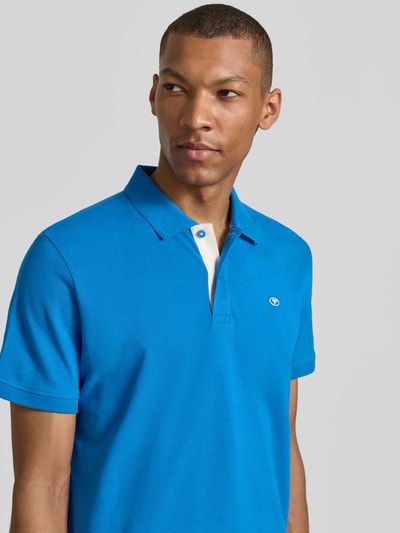 Männermodel trägt Regular Fit Poloshirt aus reiner Baumwolle von Tom Tailor in Blau, glatte Textur, Nahaufnahme Oberkörper. Herren Poloshirt.