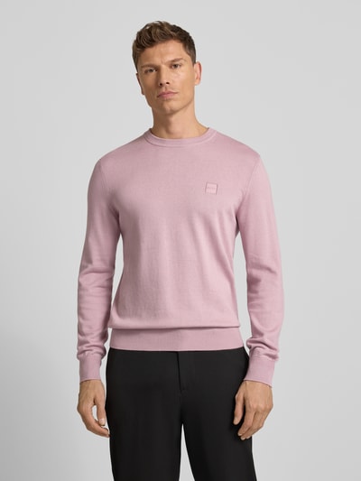 Männermodel draagt Regular Fit Pullover aus Baumwoll-Kaschmir-Mix Modell 'KANOVANO' van BOSS Orange, lichtroze, effen, grofgebreid, met label patch, lange mouwen, ronde hals, geribde boorden, Ganzkörperansicht van voren.