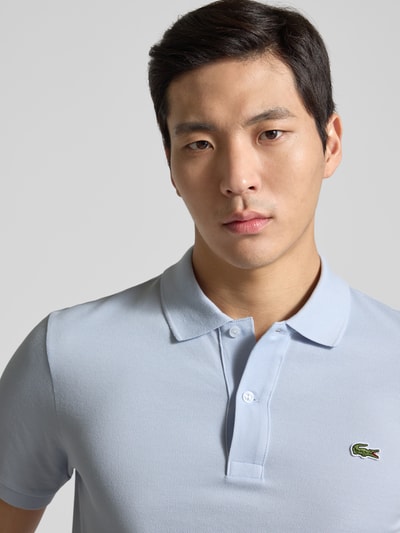 Männermodel trägt Slim Fit Poloshirt aus reiner Baumwolle von Lacoste, hellblau, Piqué, Logo-Stitching, Nahaufnahme Oberkörper.