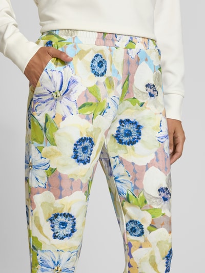 Kobiece modelka nosi Straight Fit Stoffhose aus Viskose-Mix von Christian Berg Woman, mieszanka wiskozy, kwiatowy nadruk na całej powierzchni, elastyczny pas, pastelowe kolory, skrócony krój, detal z przodu, zbliżenie na biodra.