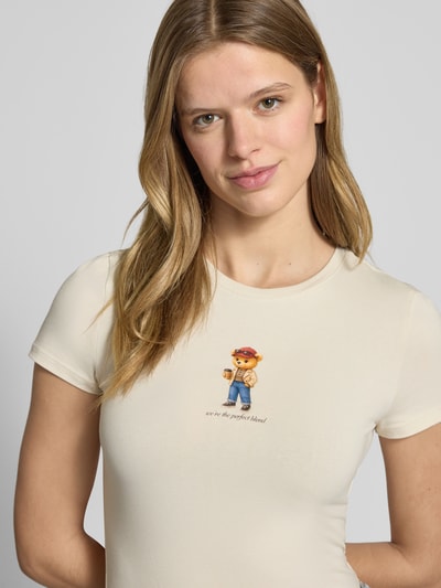 Kobiece model nosi Slim Fit T-Shirt mit Logo-Print Modell 'Sweet' von REVIEW z nadrukiem z logo, elastyczna mieszanka bawełny, okrągły dekolt, długość tyłu w rozmiarze S: 52 cm, jasny kolor, gładka faktura, zbliżenie na górę ciała.