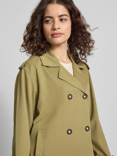 Frauenmodel trägt Regular Fit Trenchcoat-Jacke mit Reverskragen Modell 'HANNAH' von Only in Optik: Unifarben mit Schulterriegel, Rückenpasse, doppelreihiger Knopfleiste, Ärmelform Langarm und seitlichen Eingrifftaschen, Nahaufnahme Oberkörper.