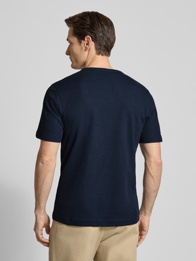 Männermodel trägt Regular Fit T-Shirt aus Baumwoll-Mix von Tom Tailor, unifarben dunkelblau, kurzarm, Piqué-Struktur, Ganzkörperansicht Rückansicht.