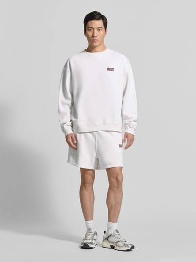 Männermodel trägt Sweatshirt mit Logo Modell 'PLIZZY' von American Vintage, Relaxed-Fit, Reine Baumwolle, Rundhalsausschnitt, Weiß, Ganzkörperansicht von vorne.