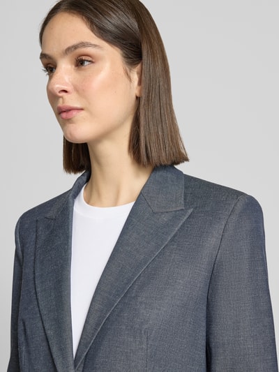 Frauenmodel trägt Relaxed Fit Blazer in eleganter Denim-Optik von Jake*s Collection in Blau mit Reverskragen und Paspeltaschen, Nahaufnahme Oberkörper. Material-Mix mit Viskose-Anteil, Knopfverschluss sichtbar.