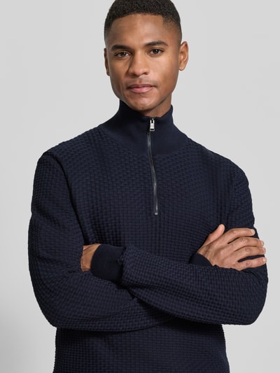 Männermodel trägt Regular Fit Troyer aus reiner Baumwolle Modell 'H-ULICIO' von BOSS, Optik: Unifarben, Strickoptik, Struktur-Muster, Troyer-Kragen mit kurzem Reißverschluss, Langarm mit geripptem Ärmel- und Rumpfabschluss, Materialverarbeitung: Rippstrick, Nahaufnahme Oberkörper.
