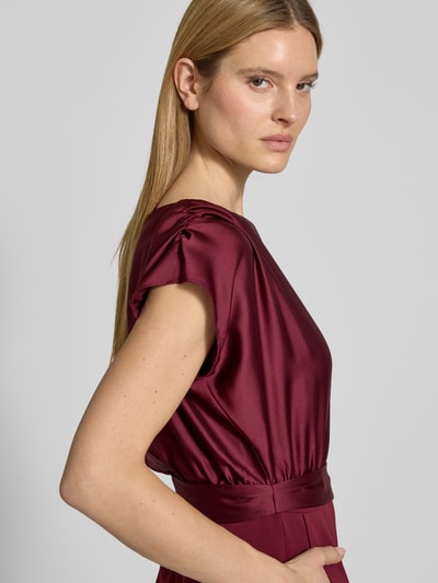 Kobiece modelka nosi Kombinezon mit Bindegürtel von SWING, mieszanka materiałów z dodatkiem streczu, taliowany krój, okrągły dekolt, z wiązanym paskiem, długość tyłu w rozmiarze 36: 40 cm, szerokość w rozmiarze 36: 34 cm, całkowita długość w rozmiarze 36: 152 cm, długość wewnętrzna nogawki w rozmiarze 36: 80 cm, bordowy kolor, gładka tekstura, detaliczny widok górnej części ciała