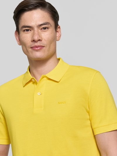 Männermodel trägt Regular Fit Poloshirt aus reiner Baumwolle Modell 'PALLAS' von BOSS in Gelb, Optik: Unifarben, Nahaufnahme Oberkörper.