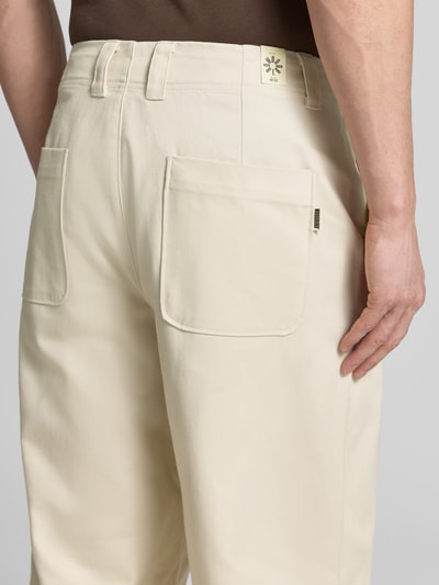Mężczyznamodel nosi chinosy 'Chino mit französischen Eingrifftaschen' von WOODBIRD z bawełny, krój loose fit, długość wewnętrzna nogawki 81 cm, szerokość w rozmiarze 32: 44 cm, wpuszczane kieszenie, kieszenie z tyłu, kolor jasny kremowy, detal zapięcia na guzik i zamek błyskawiczny, widok całej sylwetki z tyłu.