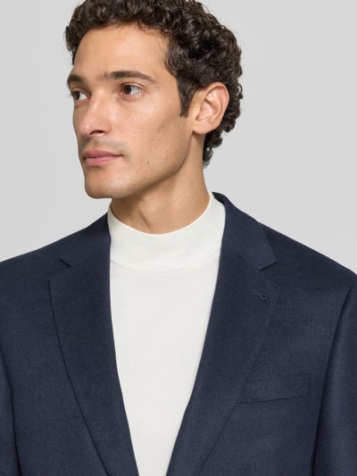 Männermodel trägt Slim Fit 2-Knopf-Sakko mit Pattentaschen von Christian Berg Men in Dunkelblau, Material-Mix mit Viskose-Anteil, Nahaufnahme Oberkörper.