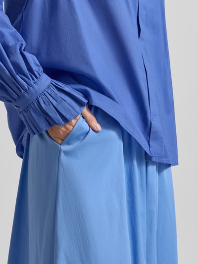 Frauenmodel trägt Midirock aus Baumwoll-Mix von Milano Italy in Hellblau, leichte A-Linie, Elastischer-Logo-Bund, Nahaufnahme Oberkörper.