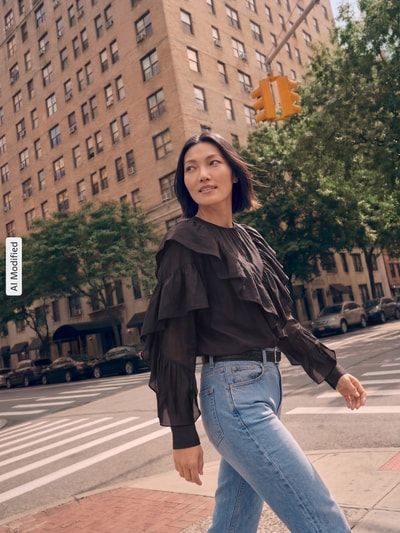 Frauenmodel trägt Regular Fit Bluse aus Lyocell-Mix von COMMA, schwarz, Rüschenbesatz, Rundhalsausschnitt, langärmelig, Ganzkörperansicht von vorne, KI-modifiziertes Bild.