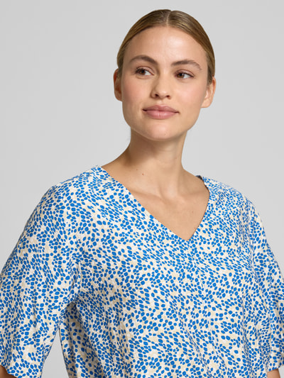 Frauenmodel trägt Relaxed Fit Blusentop aus Viskose-Mix von s.Oliver RED LABEL mit blau-weißem floralem Allover-Muster, Nahaufnahme Oberkörper.