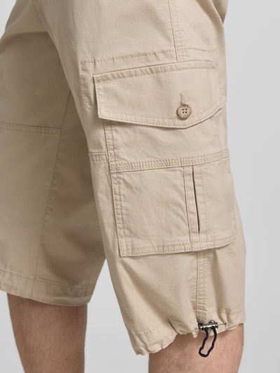 Mężczyzna nosi Capri Cargo Pants mit Pattentaschen von bugatti, bawełniany miks ze streczem, proste nogawki, beż, detal kieszeni, zbliżenie nogawki