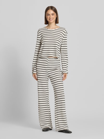 Frauenmodel trägt Relaxed Fit Langarmshirt mit Baumwoll-Anteil Modell 'EVA' von Only, Optik:Allover-Muster, Struktur, Cropped, Rundhals, langarm, Feinstrick, in Schwarz-Weiß-Tönen; Ganzkörperansicht von vorne.