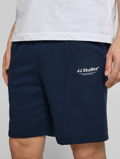 Männermodel trägt Sweatshorts mit Logo Model 'KANE' von Jack & Jones aus Baumwoll-Mix, Relaxed-Fit, Dunkelblau, Nahaufnahme Oberkörper.