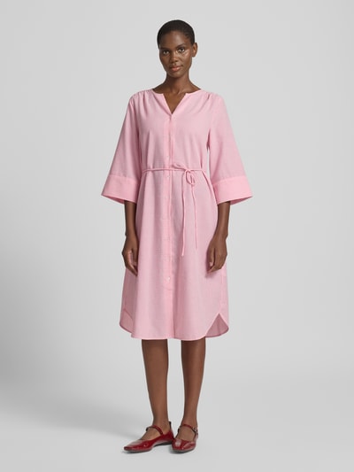 Modelka prezentuje sukienkę koszulową do kolan z wiązanym paskiem model 'IME' od B.Young, mieszanka bawełny, taliowany krój, dekolt serafino, listwa guzikowa, rękawy kimono, zaokrąglony dół, kolor różowy, długość tyłu w rozmiarze 36: 103 cm, szerokość w rozmiarze 36: 42 cm, długość rękawów w rozmiarze 36: 42 cm, widok całej sylwetki z przodu.