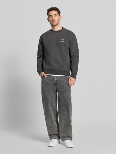 Männermodel trägt Sweatshirt mit Logo-Print Modell 'JOEL' von Samsøe Samsøe in Dunkelgrau aus Baumwoll-Mix, Relaxed Fit, Ganzkörperansicht von vorne