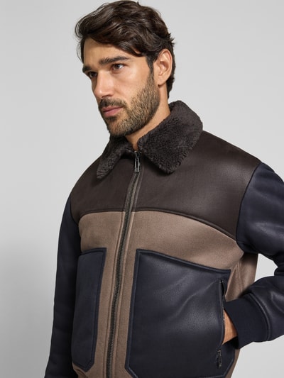 Męski model nosi Blouson in Leder-Optik mit Zweiwege-Reißverschluss od Armani Exchange, Materiał skóropodobny, krój regular fit, wykładany kołnierz z futerka, zamek błyskawiczny dwustronny, widok na górną część ciała z przodu.