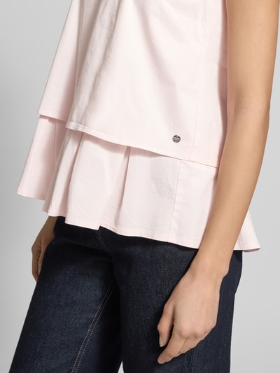 Kobiece modelka nosi Blusenshirt mit Volantsaum und Rundhalsausschnitt von Marc Cain, mieszanka bawełny i wiskozy z dodatkiem wiskozy, prosty krój, okrągły dekolt, dół obszyty falbaną, zamek błyskawiczny z tyłu, długość tyłu w rozmiarze 36: 59 cm, jasnoróżowy kolor, widoczne różne faktury tkaniny, zbliżenie na górną część ciała