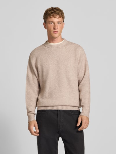 Männermodel trägt Strickpullover mit Rundhalsausschnitt Modell 'SOHO OLLIE' von JACK & JONES, beige, Struktur mit Woll-Anteil, Ganzkörperansicht von vorne.