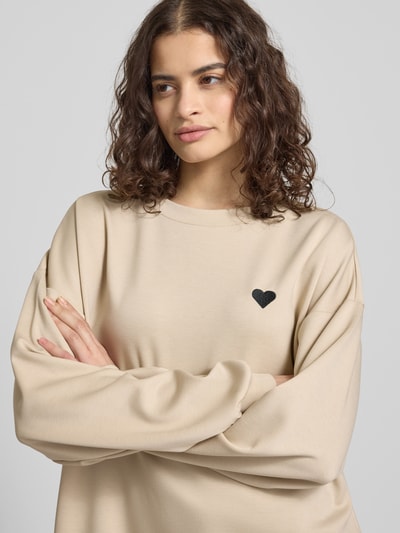 Vrouwenmodel draagt Relaxed Fit Pullover met hartborduursel model 'TALIA' van Pieces, effen, ronde hals, lange mouw, close-up bovenlichaam.