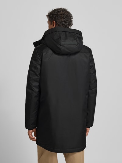 Männermodel trägt Jacke mit Pattentaschen Modell von NAUTGÅRD in Schwarz, Regular Fit, Kapuze, Rückenlänge 96 cm, Ganzkörperansicht Rückansicht.