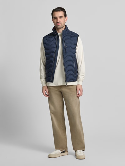 Männermodel trägt Regular Fit Steppweste mit Kapuze im Kragen von Tom Tailor in Dunkelblau, unifarben, Ganzkörperansicht von vorne.