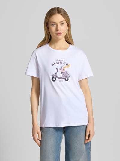 Frauenmodel trägt T-Shirt mit Motiv und Ziersteinbesatz von Liu Jo White, reine Baumwolle, Relaxed Fit, Rundhalsausschnitt, Ganzkörperansicht von vorne