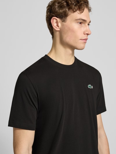 Männermodel trägt Regular Fit T-Shirt aus Baumwoll-Mix von Lacoste Sport in Schwarz mit Logo-Applikation, Nahaufnahme Oberkörper.