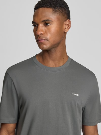 Männermodel trägt Regular Fit T-Shirt aus reiner Baumwolle Modell 'DERO222' von HUGO, Optik: Unifarben, Label-Print, Nahaufnahme Oberkörper.