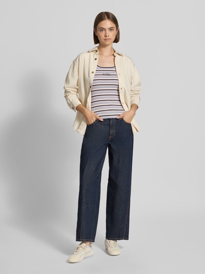 Frauenmodel trägt Slim Fit Top aus Baumwoll-Mix mit Logo-Stitching von GUESS Jeans mit Rundhalsausschnitt, gestreift, Ganzkörperansicht von vorne.
