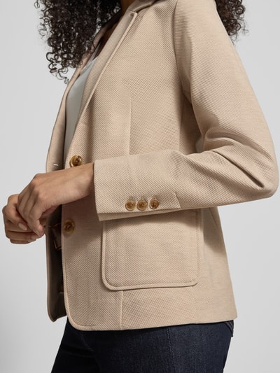 Frauenmodel trägt Regular Fit Blazer mit Viskose-Anteil Modell 'Vega Daisi' von MOS MOSH, beige, strukturierte Oberfläche, Nahaufnahme Oberkörper, Elastischer-Material-Mix, Reverskragen, aufgesetzte Taschen, 2-Knopfleiste, Rückenlänge 60 cm, Brustweite 45 cm, Ärmellänge 63 cm, Größe 36.