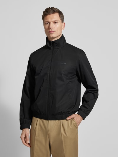 Männermodel trägt Jacke mit Stehkragen und Reißverschluss von CK Calvin Klein in Schwarz, Regular Fit, Eingrifftaschen, Ganzkörperansicht von vorne.